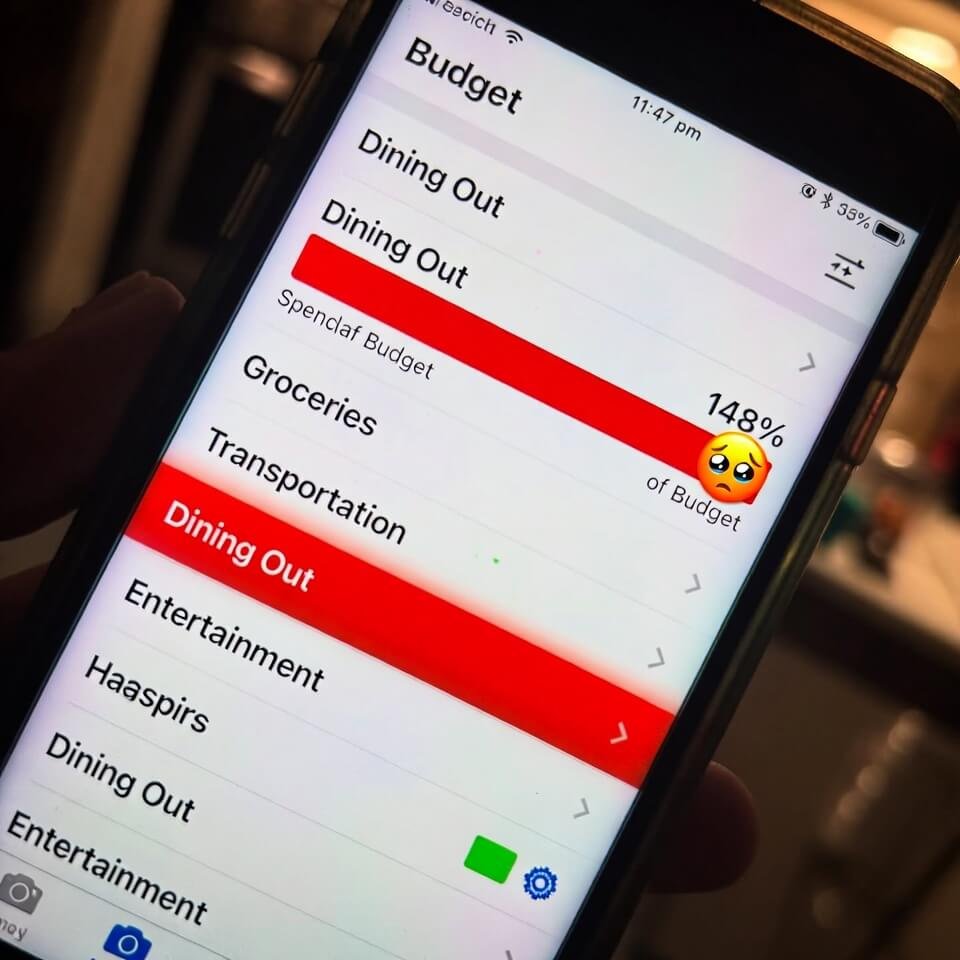 Budget app showing Dining Out at 148% with crying emoji

