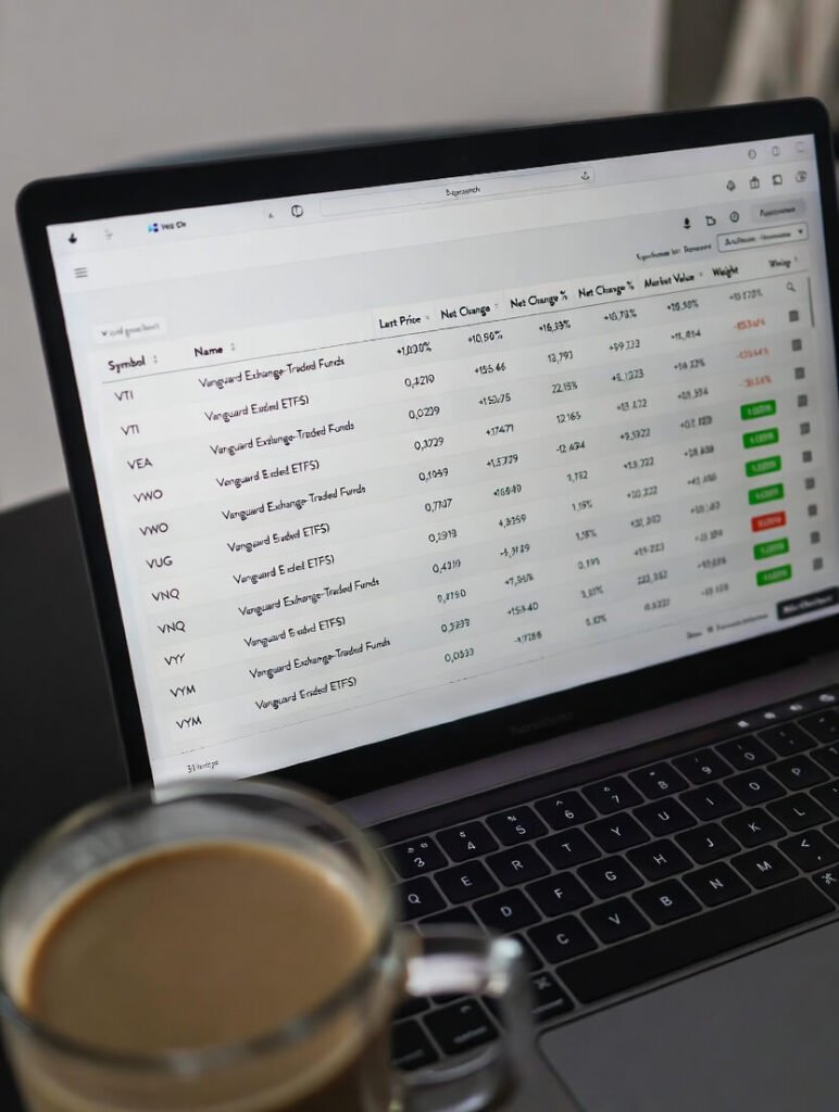 Crooked laptop screen showing Vanguard ETF portfolio and coffee mug